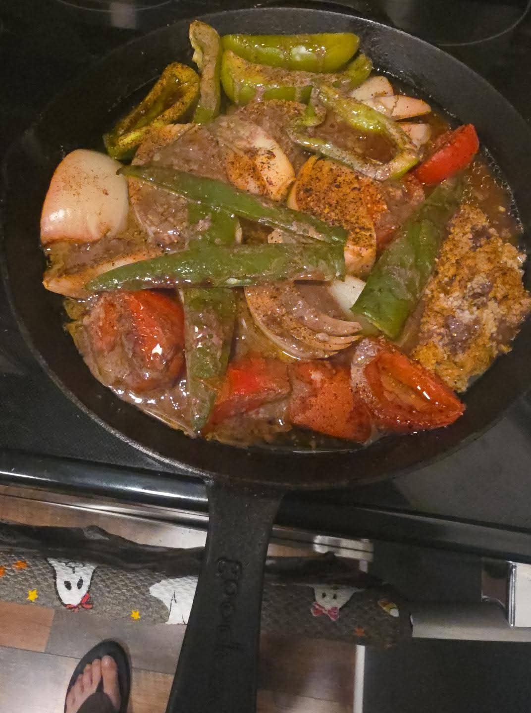 Smoked tomatoes, onion, peppers, and meat drippings in a cast-iron skillet.