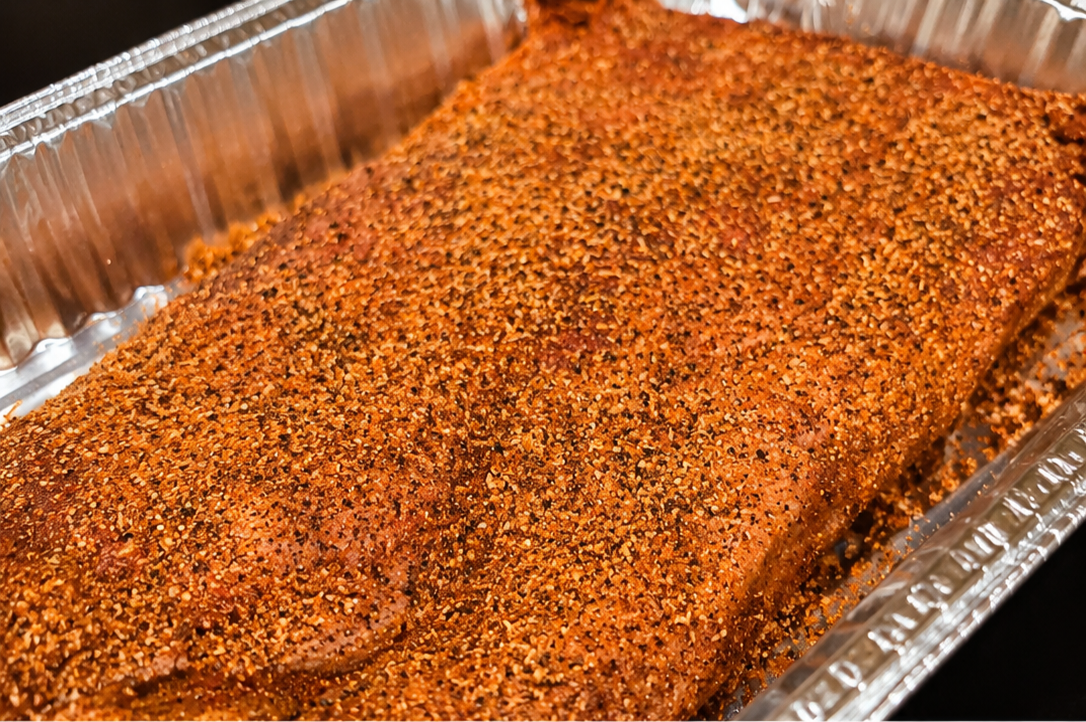 Raw brisket coated generously with Smoking Ray's Magic Cow Dust seasoning